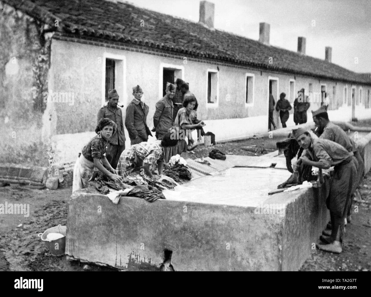 Foto de combatientes republicanos lavando su ropa durante la batalla de Talavera de la Reina, detrás de la fachada de El Bravo-Orteria. Las mujeres a lavar, soldados en uniforme y un lavado de comedero. Foto de stock