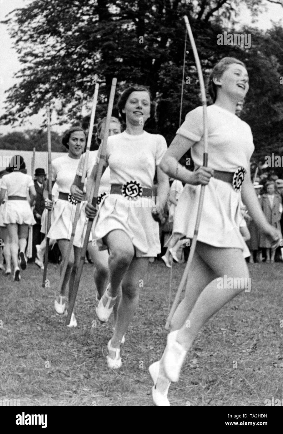 durante-la-reunion-de-la-organizacion-nazi-kraft-durch-freude-sstrength-a-traves-de-la-alegria-con-sede-en-hamburgo-la-mujer-del-bochum-gaugruppe-realizar-ejercicios-deportivos-con-arcos-y-flechas-el-emblema-del-frente-de-trabajo-aleman-aparece-en-su-cinturon-ta2hdn.jpg