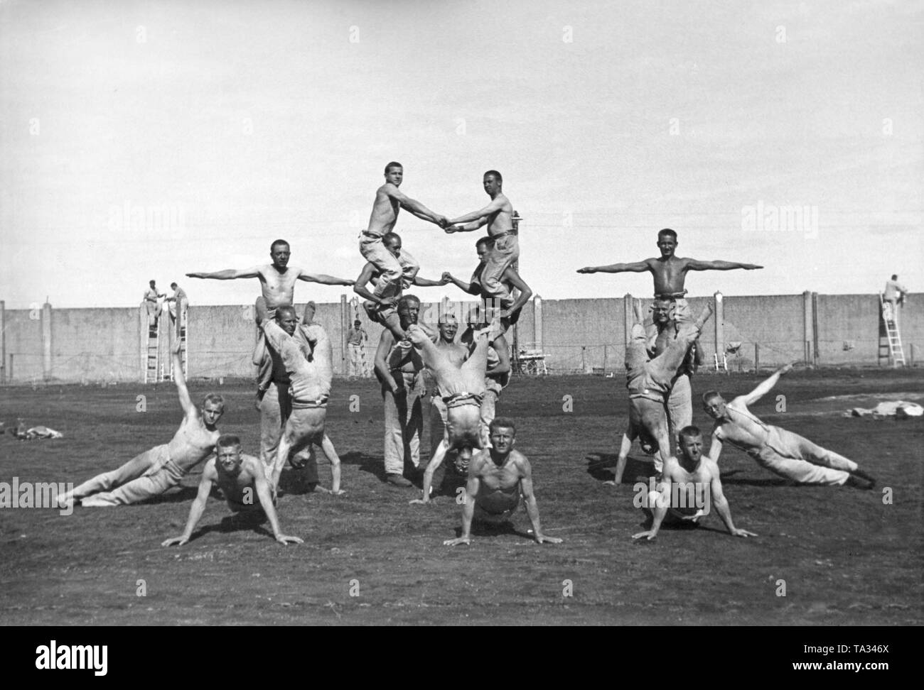 Los prisioneros haciendo gimnasia en el campo de concentración. En el fondo de la pared del campo de concentración. Esta foto, al igual que muchos otros, fue hecha para fines de propaganda nazi. Foto de stock
