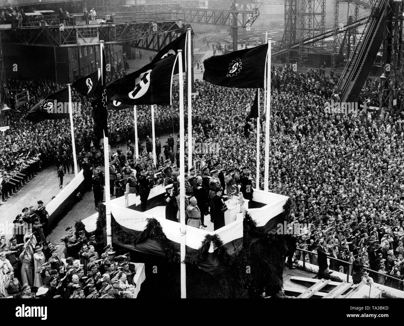 Durante el lanzamiento de la primera nave KdF, que fue nombrado después de la Swiss Landesgruppenleiter (grupo nacional líder), Wilhelm Gustloff, Nazi celebridades son recibidos con el saludo hitleriano sobre una plataforma de bautizo en la Blohm & Voss en el puerto de Hamburgo. De izquierda a derecha: Robert Ley, Eduvigis Gustloff (viuda de Wilhelm Gustloff ), Adolf Hitler, Heinrich Himmler. La bandera con la esvástica y la bandera del Frente de trabajo alemán están soplando. Foto de stock