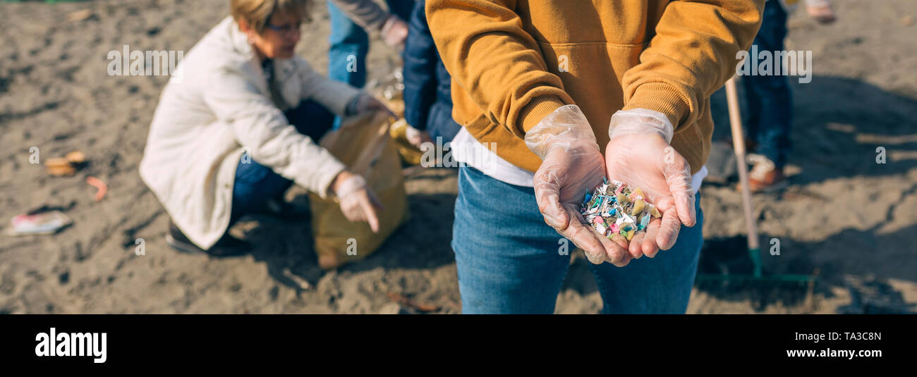 Con las manos en la playa microplastics Foto de stock
