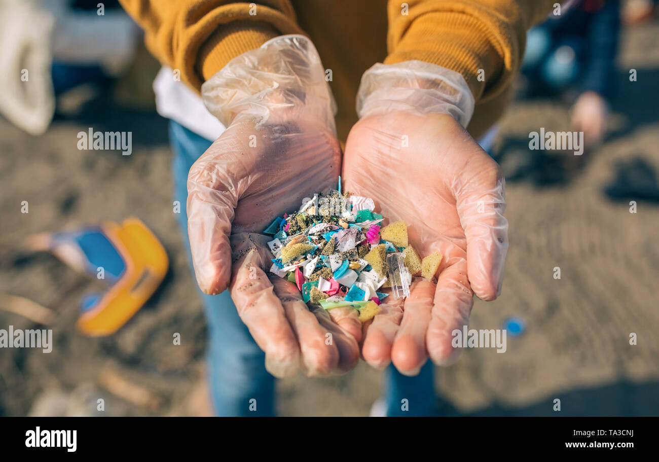 Con las manos en la playa microplastics Foto de stock
