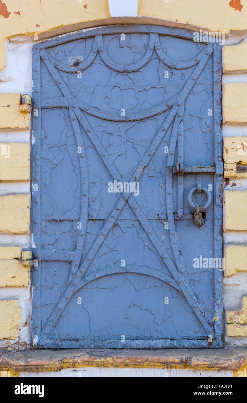 Antigua puerta de hierro forjado con remaches y viejas pelando la pintura  azul con bastidor de pared amarilla Fotografía de stock - Alamy