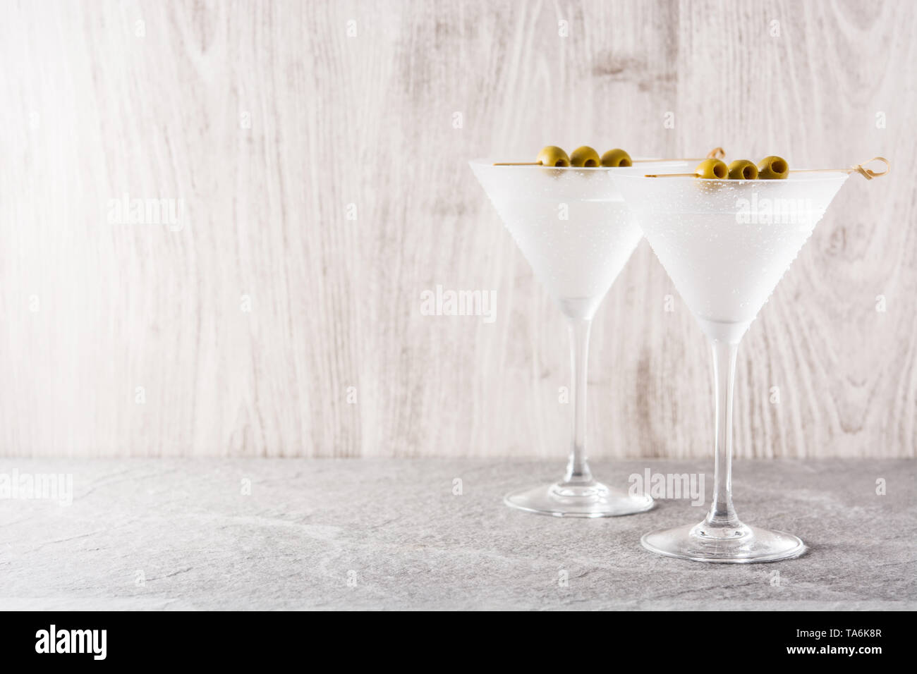 Classic Dry Martini con aceitunas sobre fondo gris. Copyspace Foto de stock