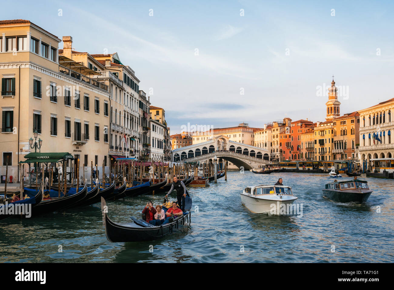 Venecia, Italia - 10 de mayo de 2019: El Puente de Rialto en el Gran Canal con góndolas y lanchas taxi al atardecer, Venecia, Italia Foto de stock