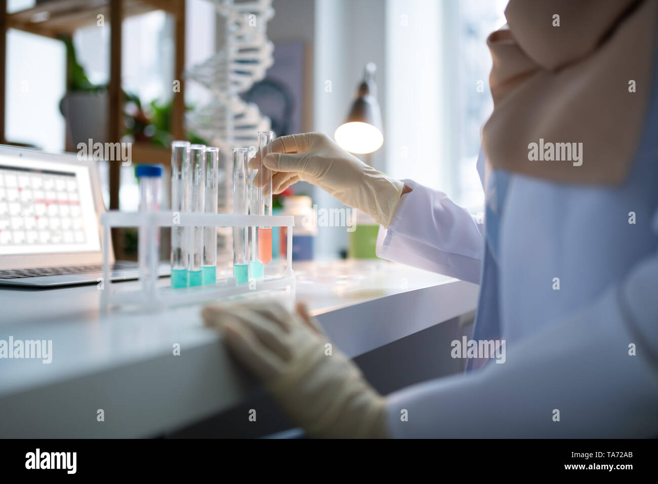 Farmacia vistiendo bata blanca y guantes trabajando en el laboratorio. Foto de stock