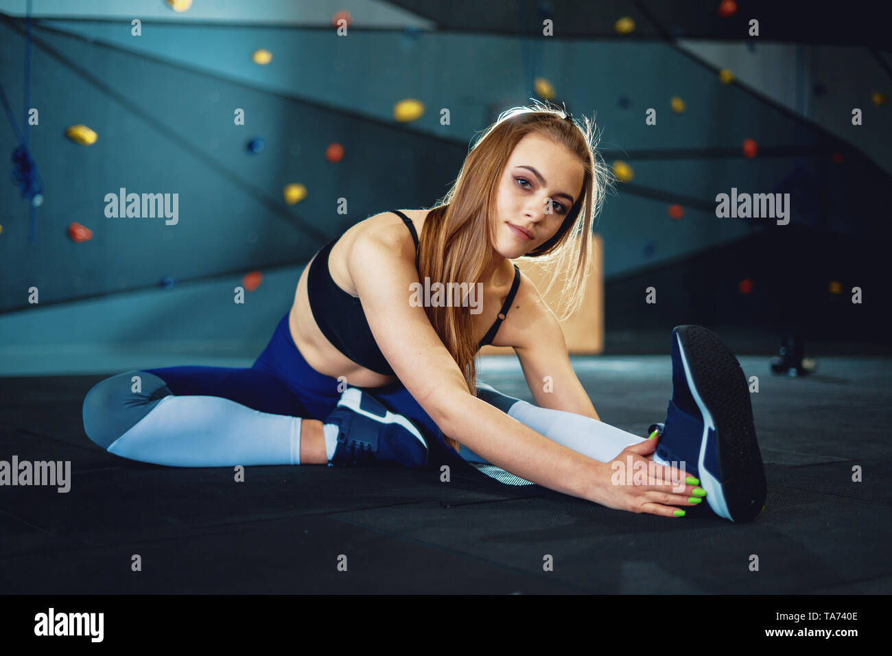 Estirando el gimnasta chica haciendo exercizes calentamiento. Vista del atractivo joven haciendo deporte en el gimnasio crossfit Foto de stock