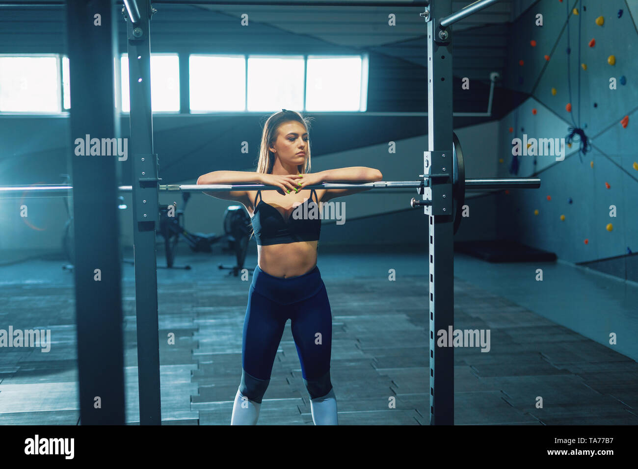 El gimnasta chica haciendo squat barbell. Vista frontal del atractivo joven Foto de stock