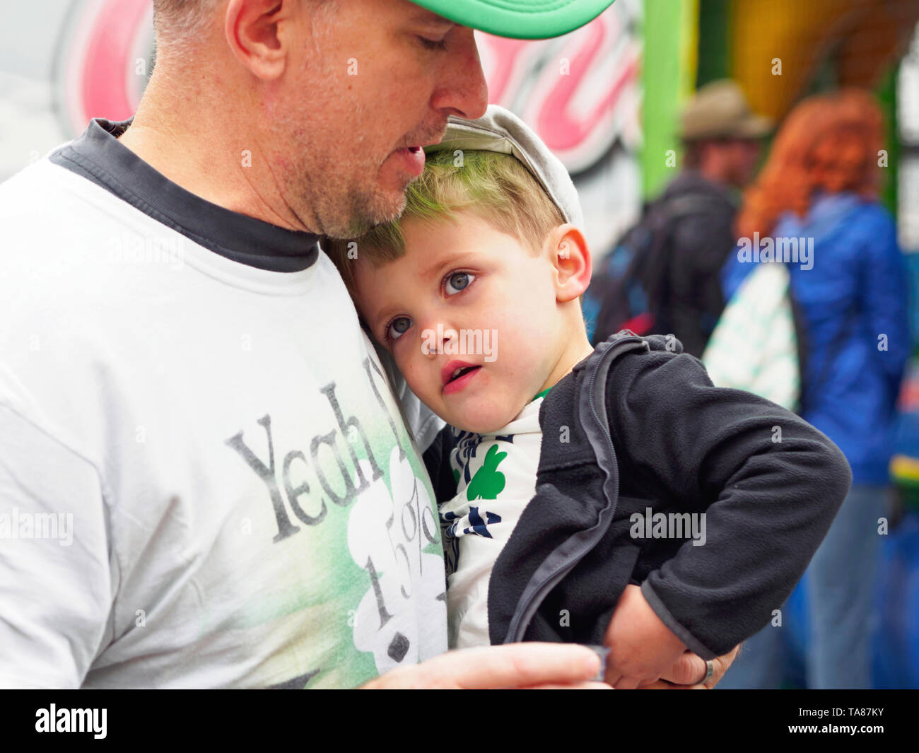 Little Boy es retenido por su padre en el año 2019 el Día de San Patricio, Block Party en Corpus Christi, Texas, Estados Unidos. Foto de stock