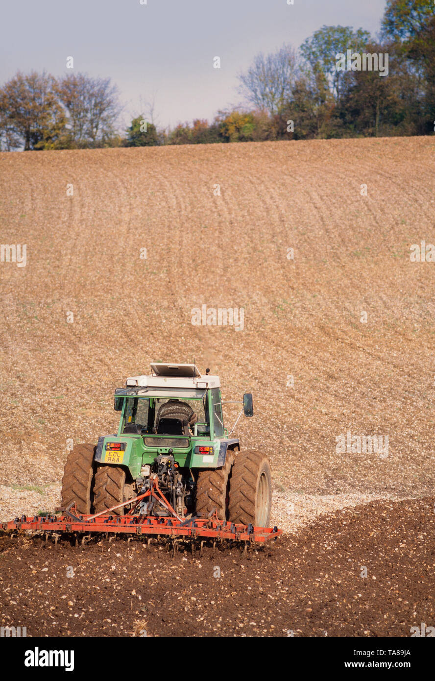 Agricultura, tractor arando un terreno cultivable, sol brillante. Foto de stock