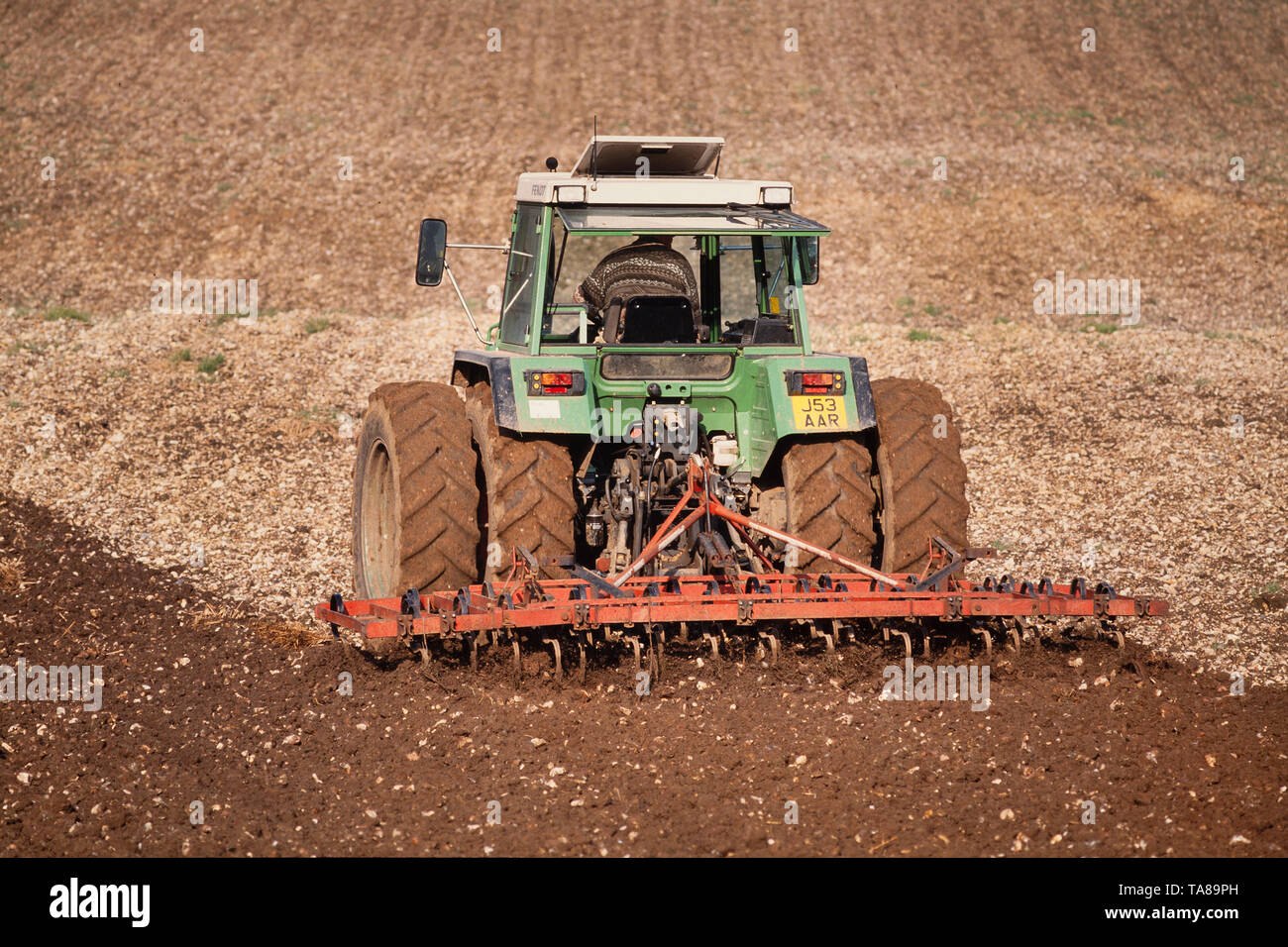 Agricultura, tractor arando un terreno cultivable, sol brillante. Foto de stock