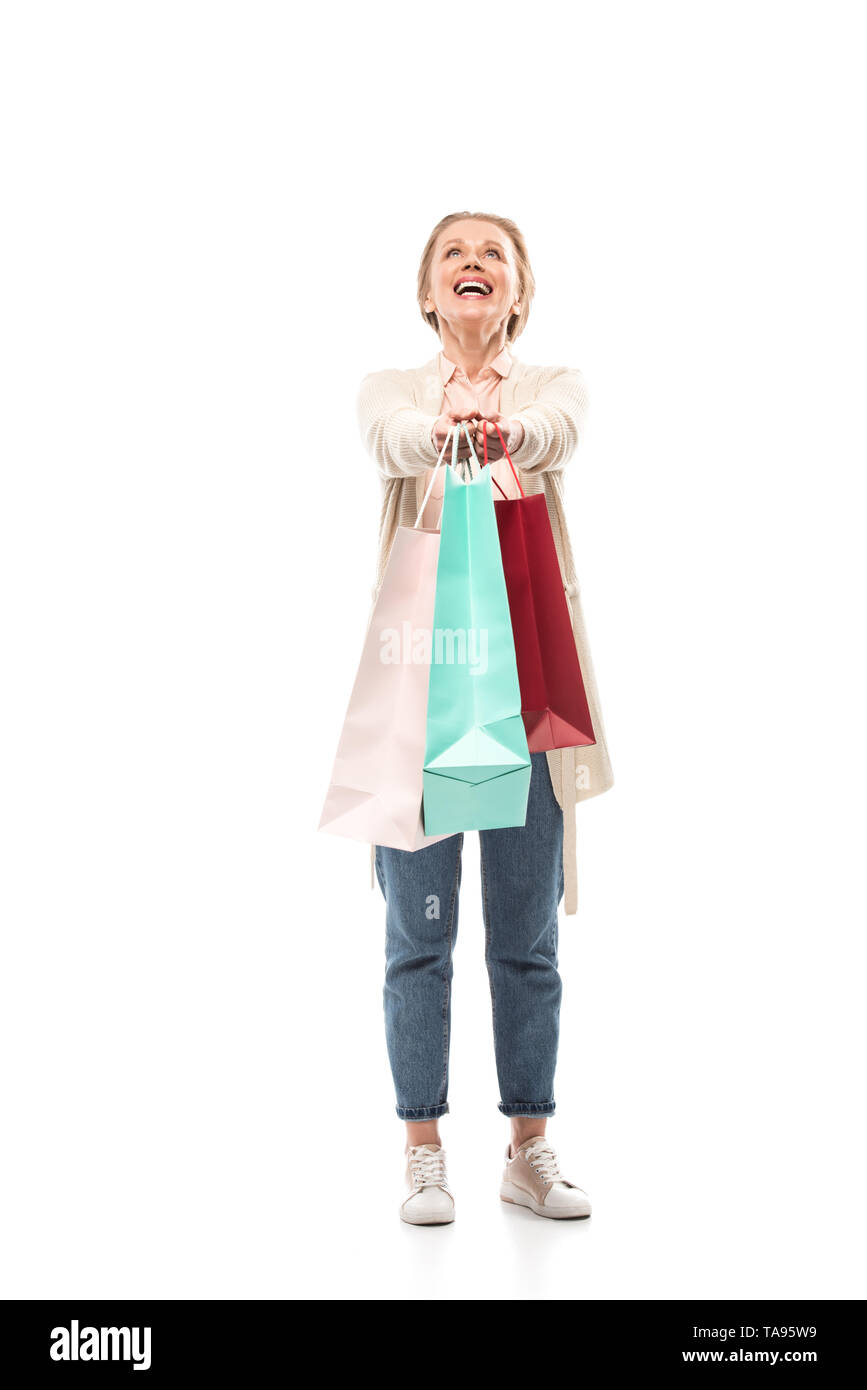 Feliz mujer de mediana edad con bolsas de compras sobre blanco Foto de stock