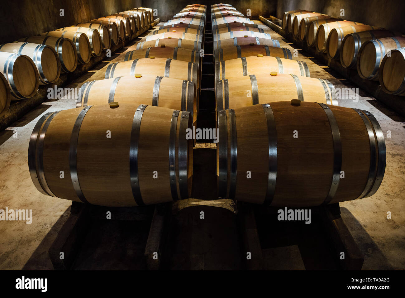 Una bodega de maduración del vino en barricas de roble alineados. Foto de stock
