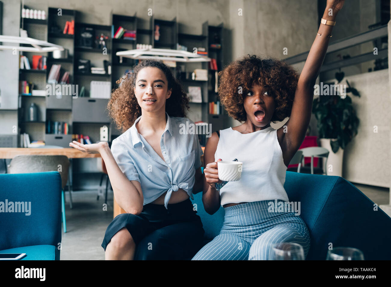 Dos jóvenes mujeres multirraciales divirtiéndose y mirando la cámara: amistad, alegre, interacción Foto de stock