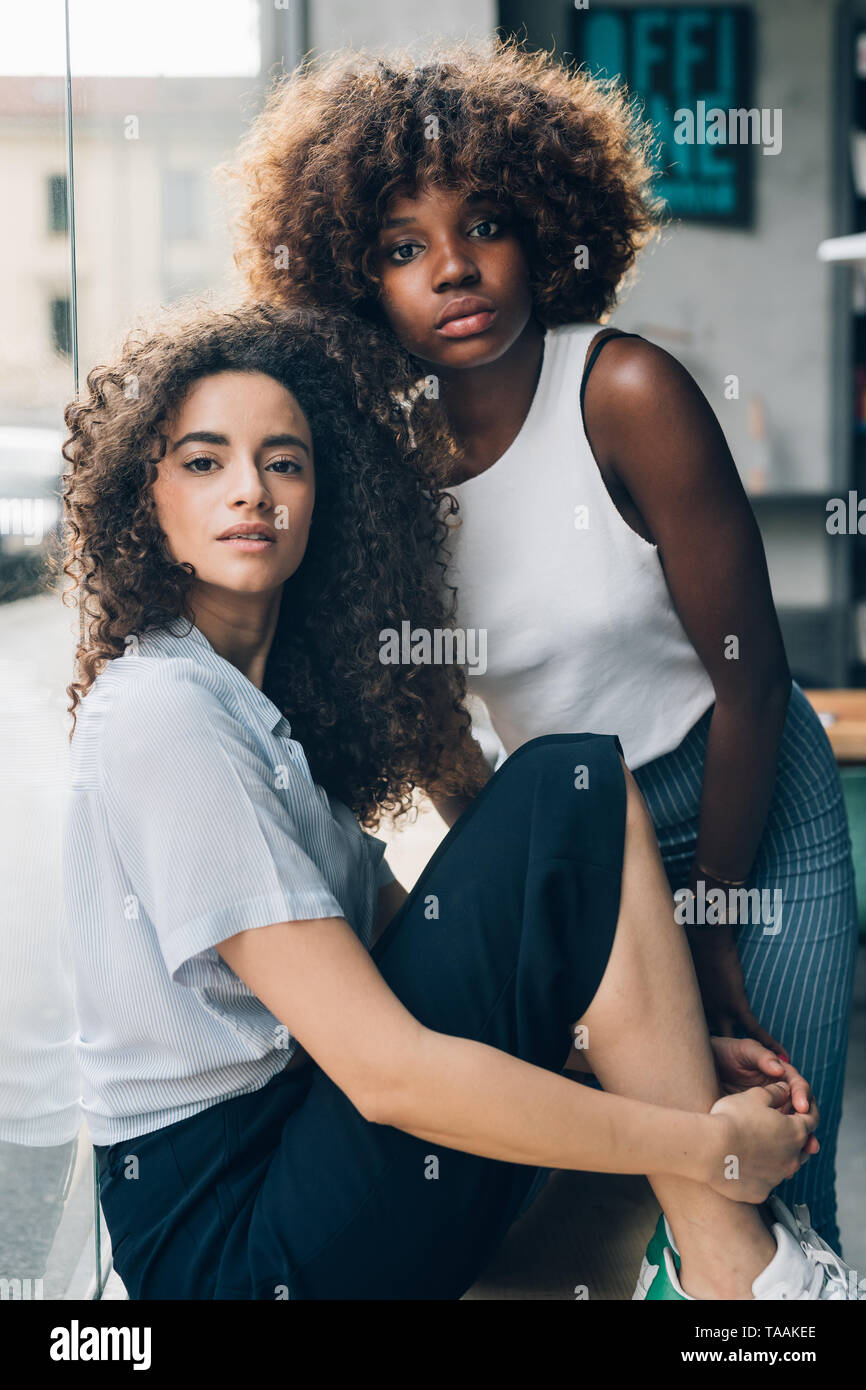 Dos jóvenes multirracial y rizado mujer sentada y mirando la cámara-, la nueva generación de jóvenes, la emancipación Foto de stock