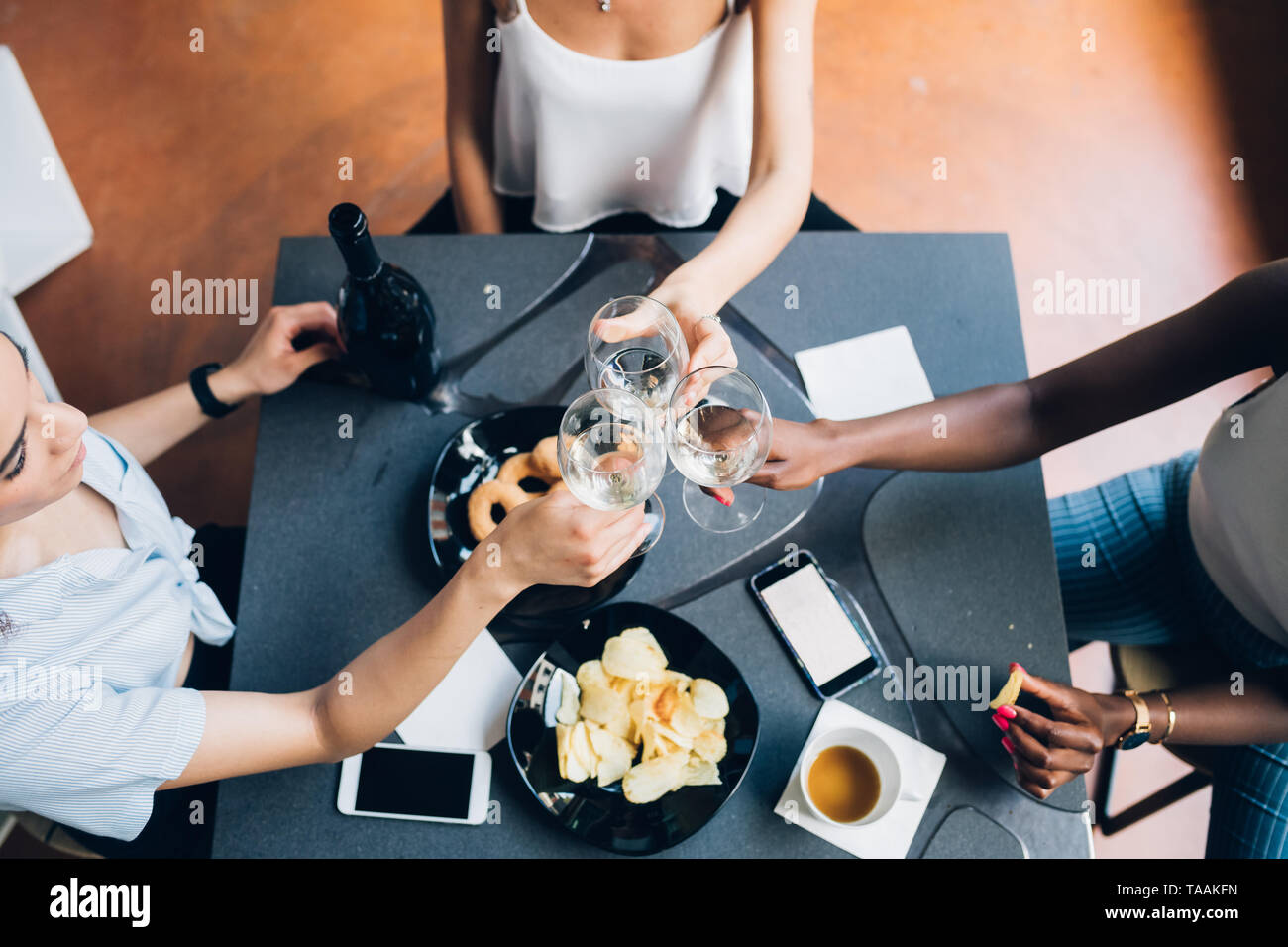 Jóvenes mujeres sentadas multirracial y beber juntos interiores - amistad, alegre, celebración Foto de stock