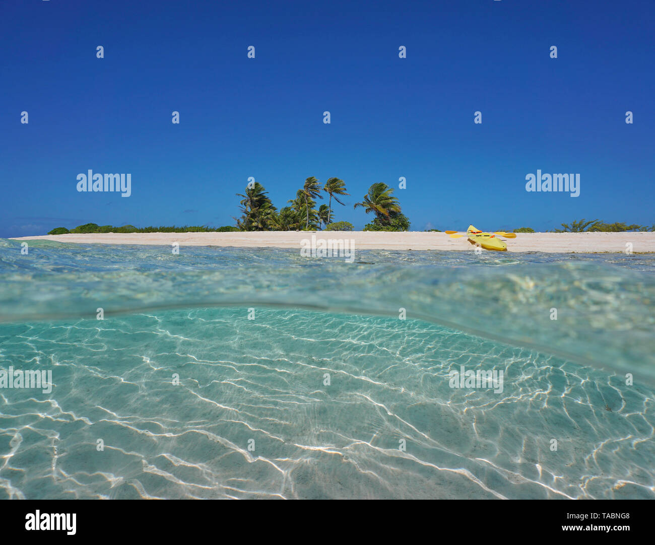 Isla tropical de arena con un kayak de mar en la playa de arena y submarinas, Polinesia francesa, Océano Pacífico, vista dividida por la mitad y bajo el agua. Foto de stock