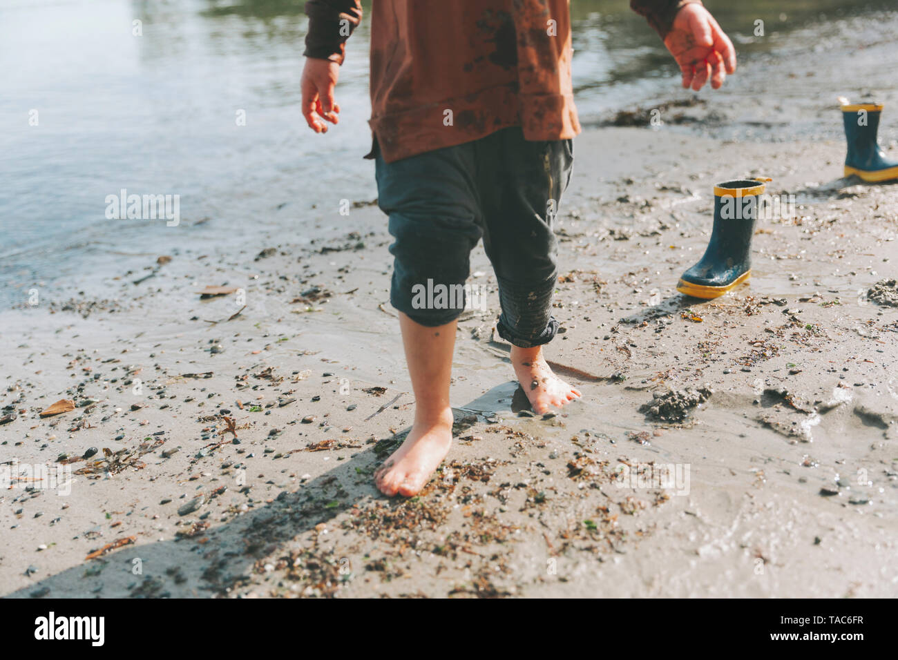 Niño jugando en la playa, caminar descalzo en el barro Foto de stock