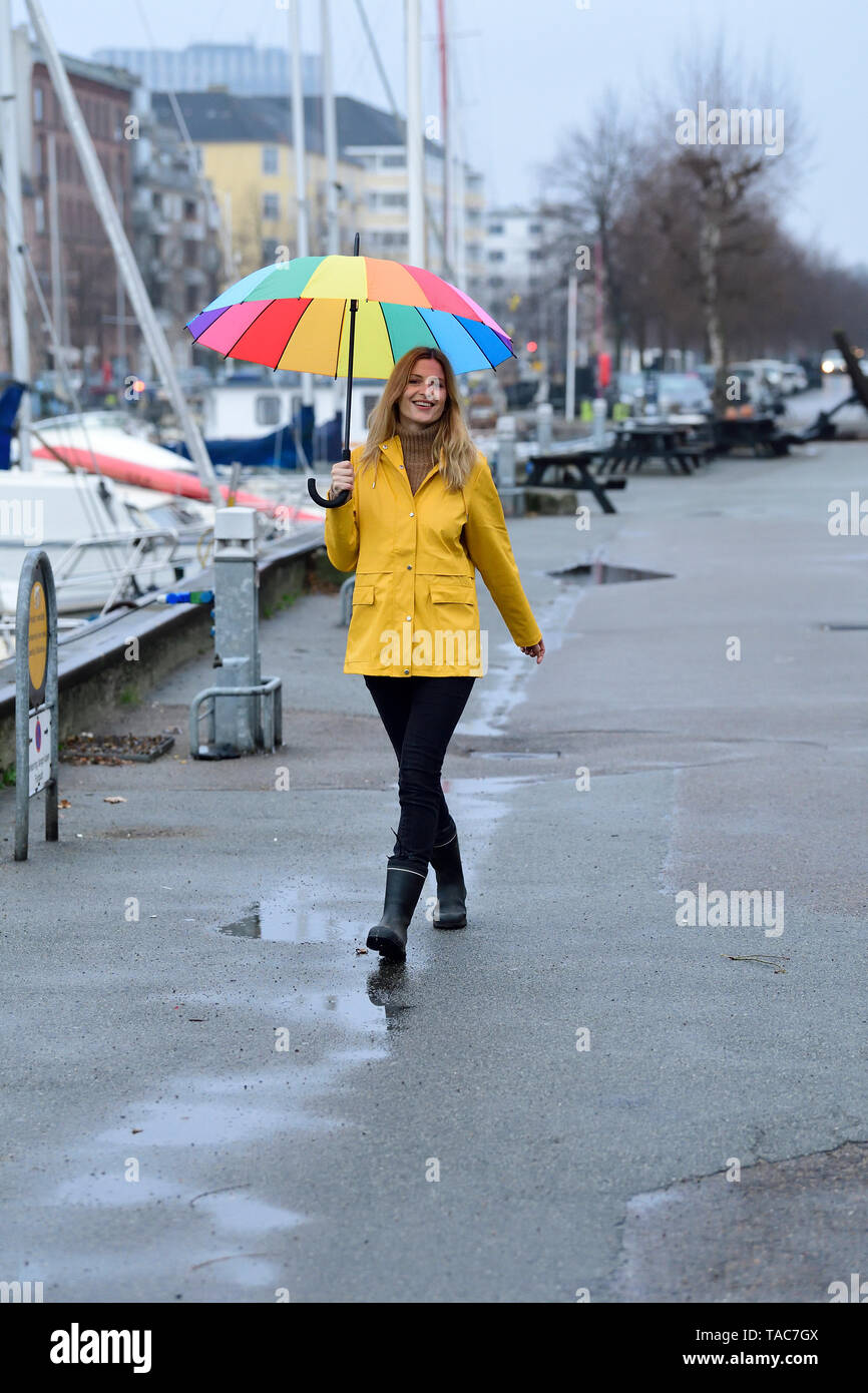 Dinamarca, Copenhague, mujer alegre y con coloridos paraguas paseando en el puerto de la ciudad Foto de stock