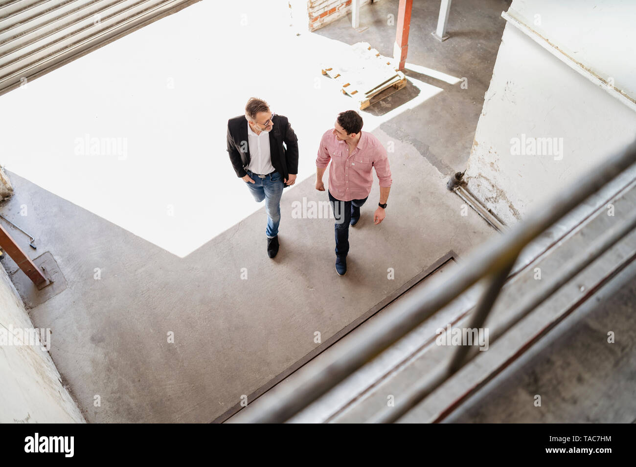 Vista de pájaro de dos hombres caminando en la bahía de carga en una fábrica Foto de stock