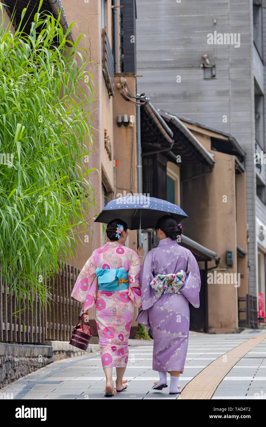 Las mujeres vestidas con el traje tradicional (kimono) caminar sobre la calle alrededor de los edificios tradicionales en Kyoto, Japón Foto de stock