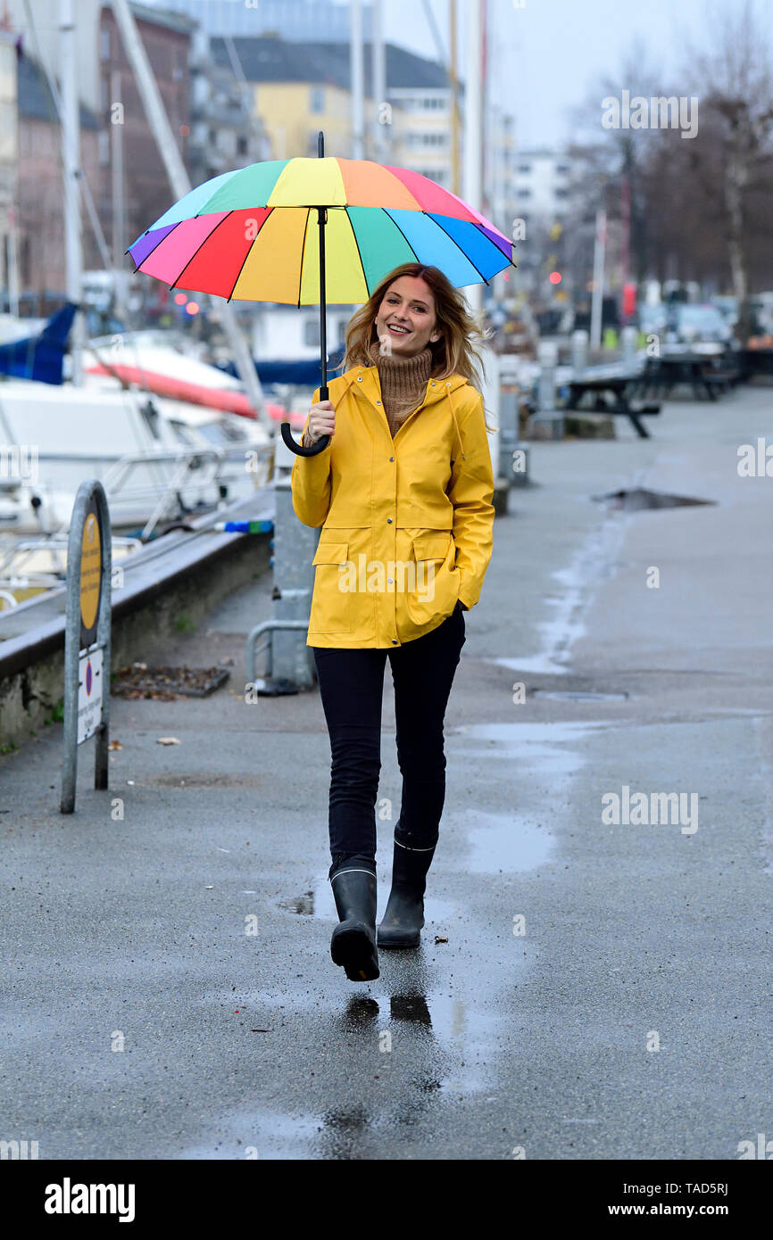 Dinamarca, Copenhague, mujer alegre y con coloridos paraguas paseando en el puerto de la ciudad Foto de stock