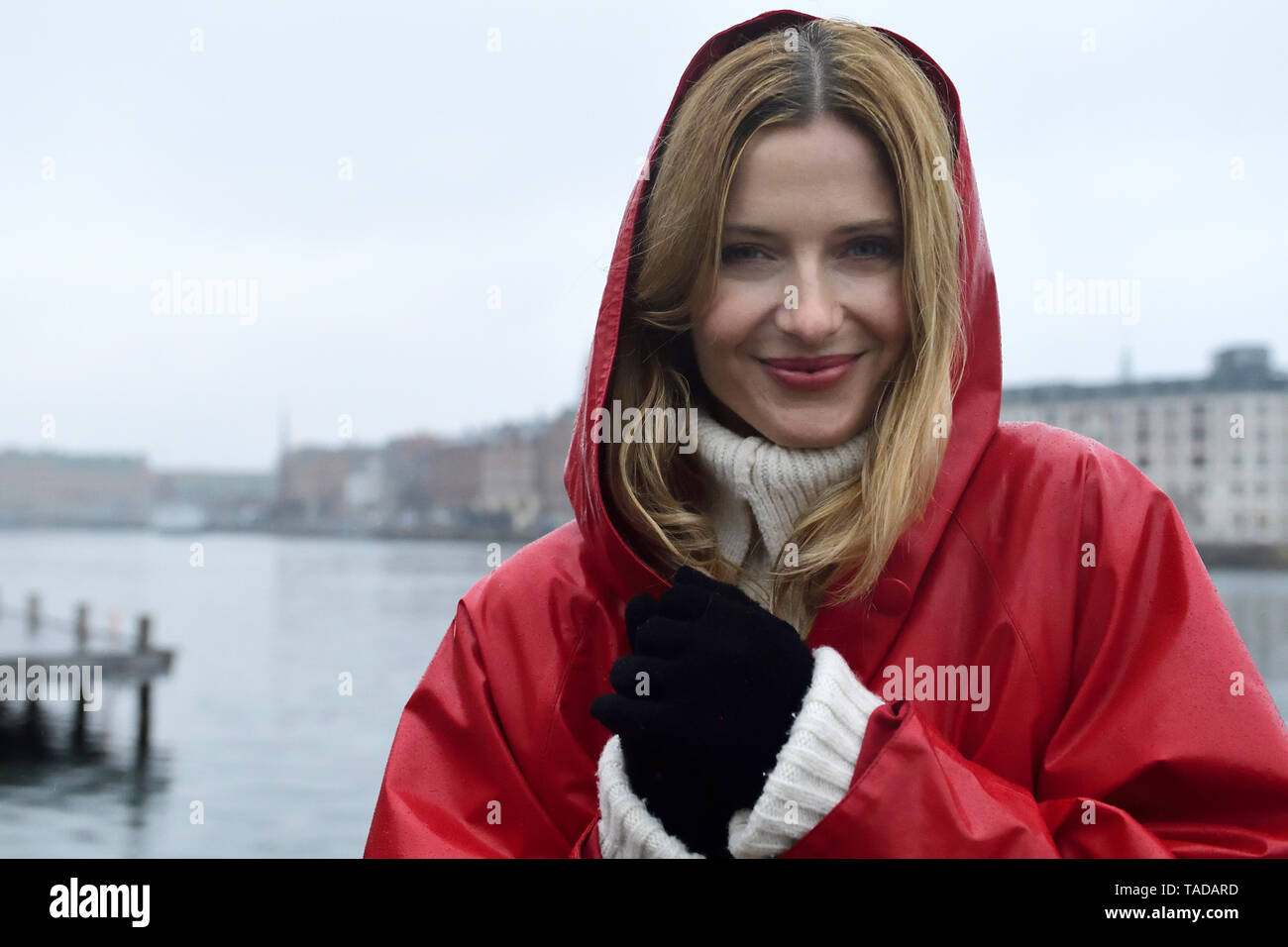 Dinamarca, Copenhague, retrato de mujer sonriente en la Costanera en un día lluvioso Foto de stock