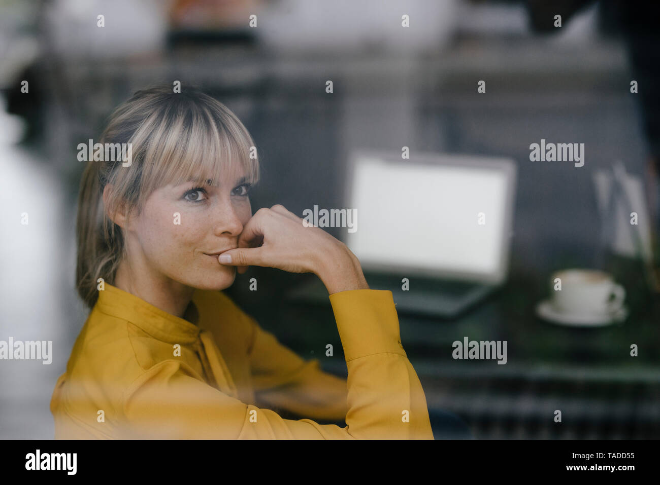 La empresaria rubia sentada a la ventana, pensando Foto de stock