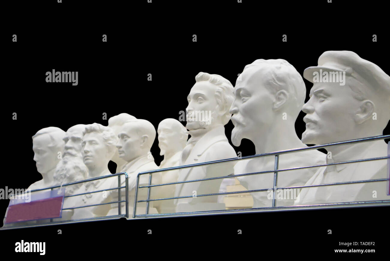 Los bustos de yeso de algunos históricos y personas populares sobre un estante de fabricación aislados en negro Foto de stock
