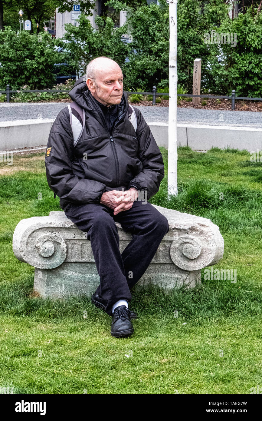 Anciano sentado en el pedestal de la antigua flora monumento en plaza Steinplatz, Charlottenburg Berlín Foto de stock