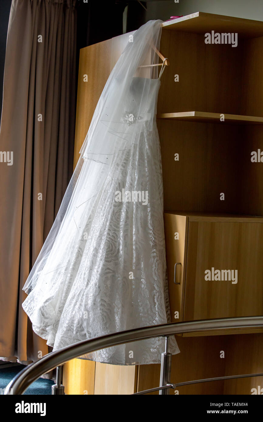 Vestido blanco colgando en el armario de madera. Blanco vestido nupcial en el rack en el armario. Vestidos de boda para la novia. Foto de stock