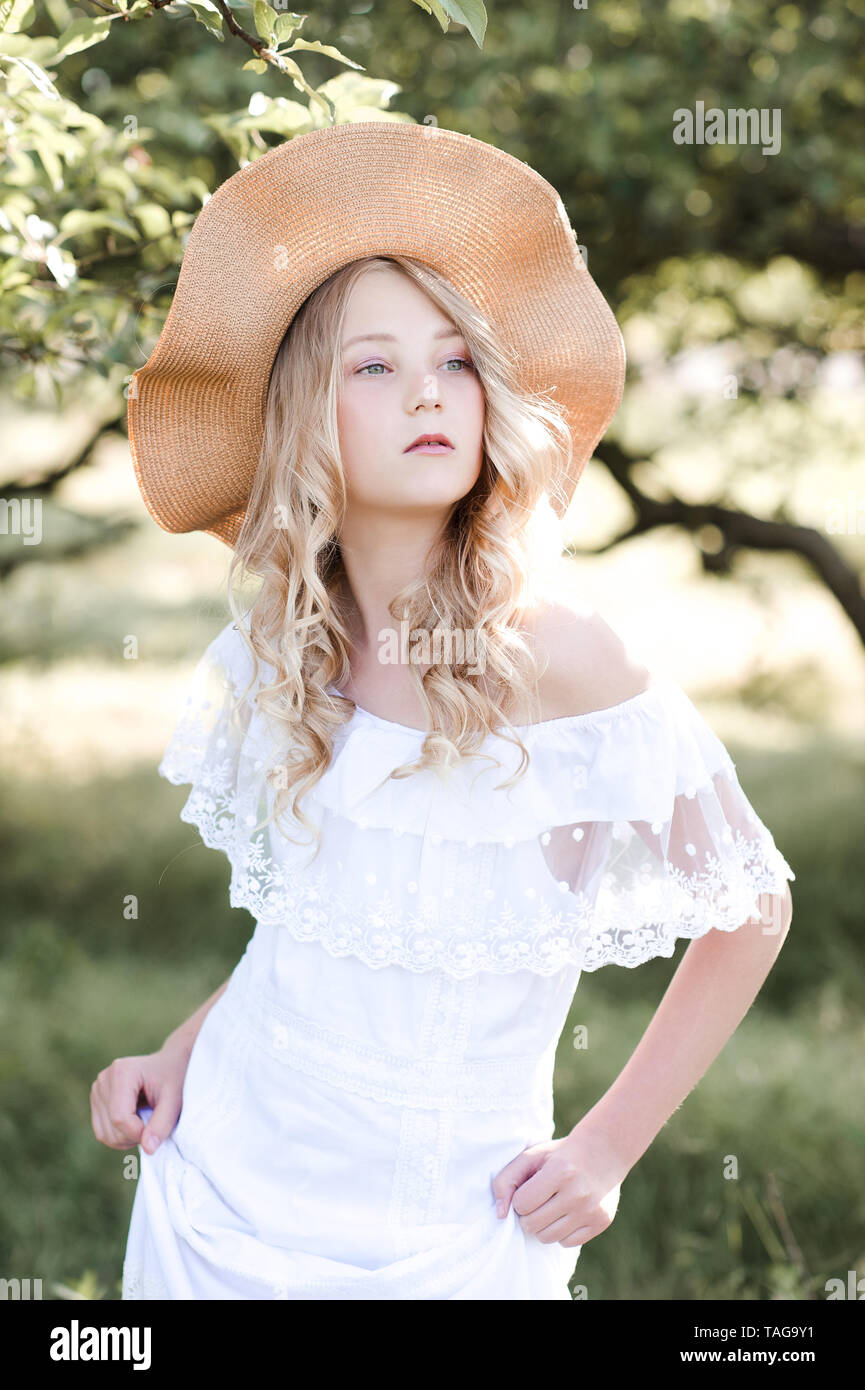 Hermosa rubia chica 16-17 años vestidos elegantes vestidos de blanco y  sombrero de caminar en el parque. El Romance Fotografía de stock - Alamy