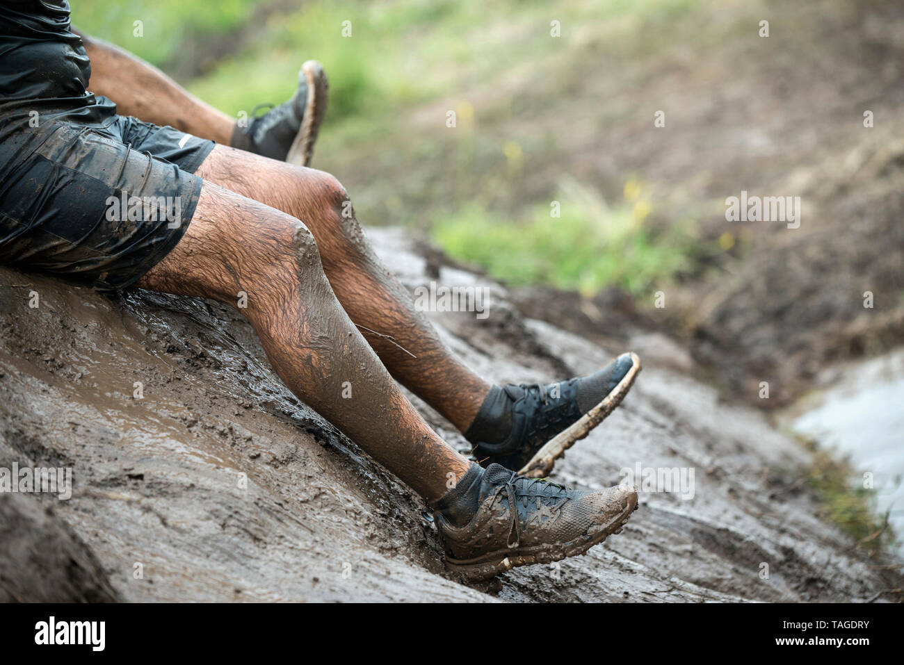 SOFIA, Bulgaria - 07 Julio 2018 - un hombre se desliza a través de una ladera fangosa a caer en una piscina de barro en una carrera de resistencia Foto de stock