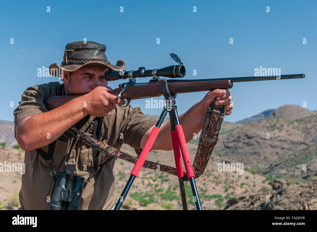 Un cazador profesional apunta una pistola rifle apoyado por un trípode en  un juego granja en Namibia Fotografía de stock - Alamy