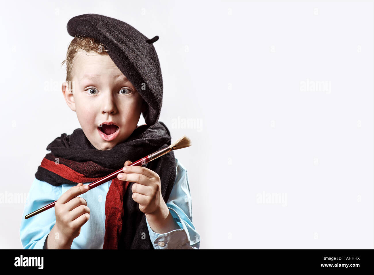 leninismo golpear preámbulo Niño alegre artista boina negra, bufanda y con un pincel en su boca sobre  un fondo de luz Fotografía de stock - Alamy