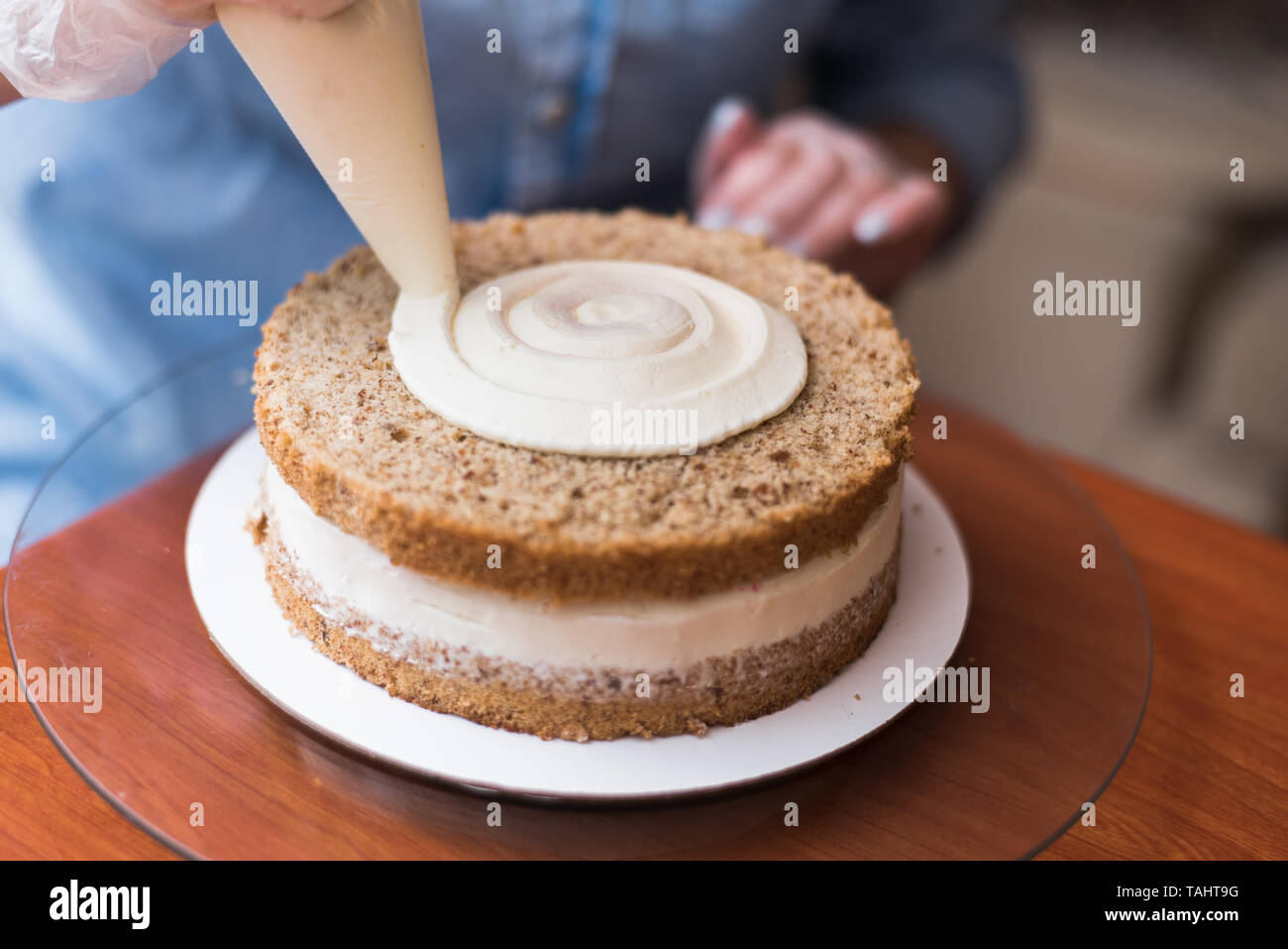 Chica Chef de Pastelería, hace un pastel de boda con sus propias manos y aprieta la crema sobre la torta de capas. Copie el espacio. El enfoque selectivo. Foto de stock
