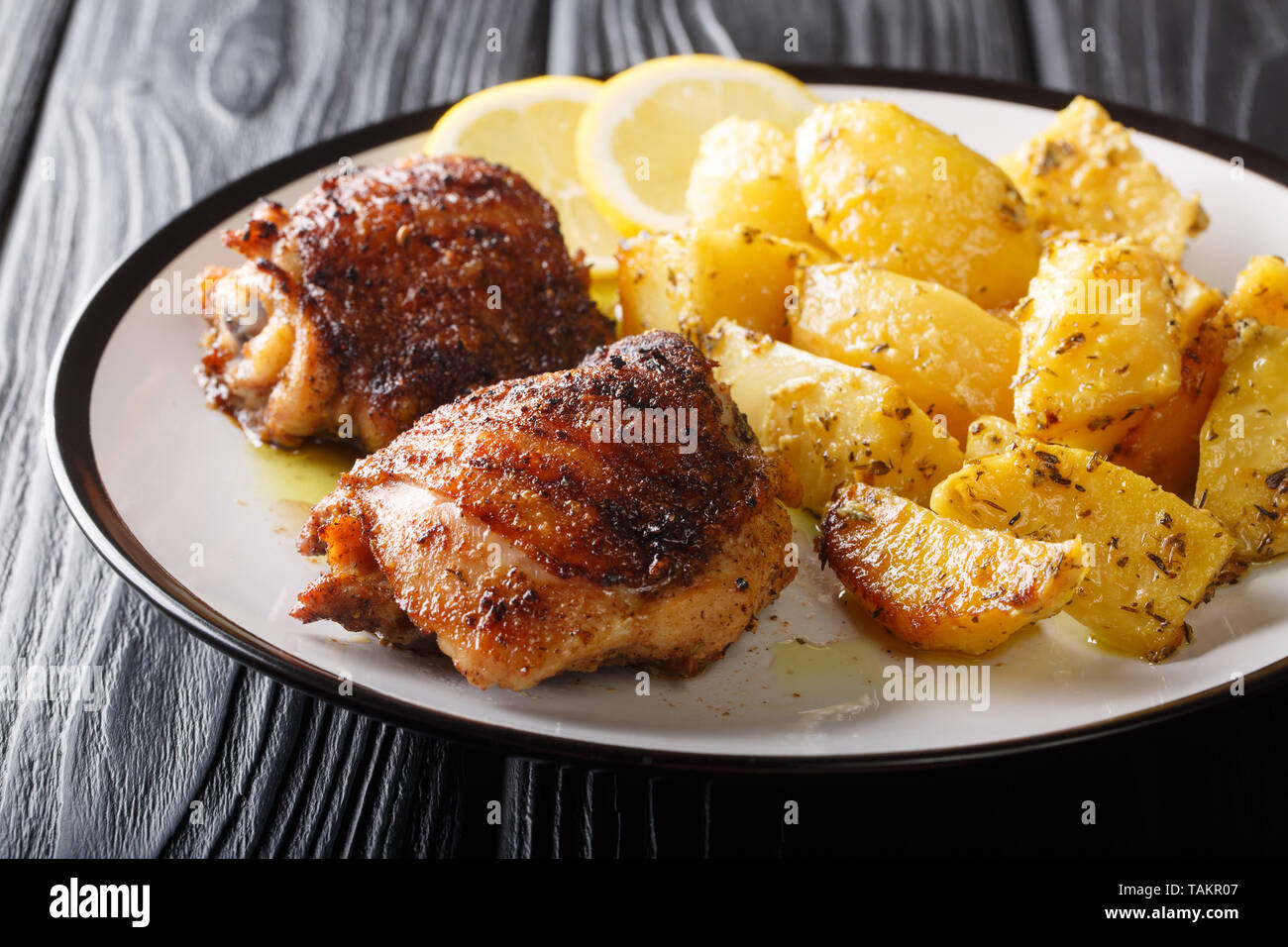 Plato principal: Muslos de pollo a la parrilla Servido con patatas ajo limón delicioso primer plano horizontal en una placa. Foto de stock