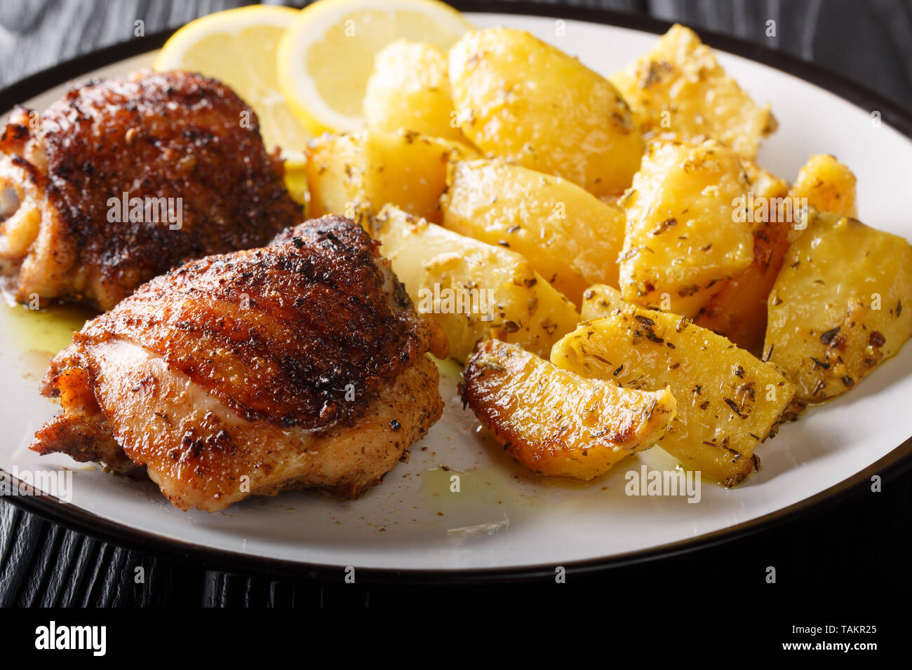 Muslos de pollo a la parrilla Servido con patatas ajo limón delicioso primer plano horizontal en una placa. Foto de stock