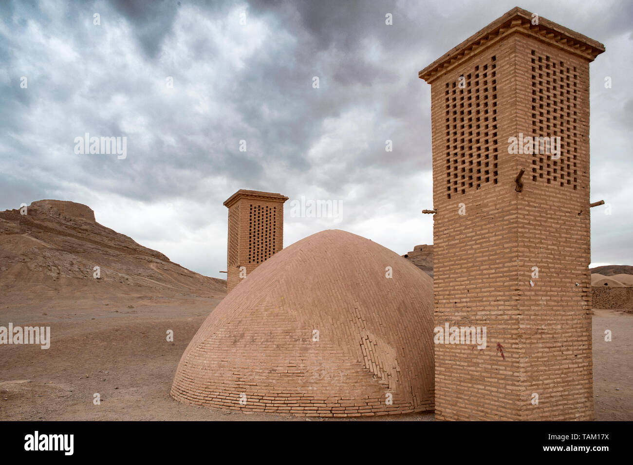Las torres de viento utilizados como un sistema de refrigeración natural para el depósito de agua en la arquitectura tradicional iraní. Torre de silencio en el fondo. Yazd, Irán Foto de stock