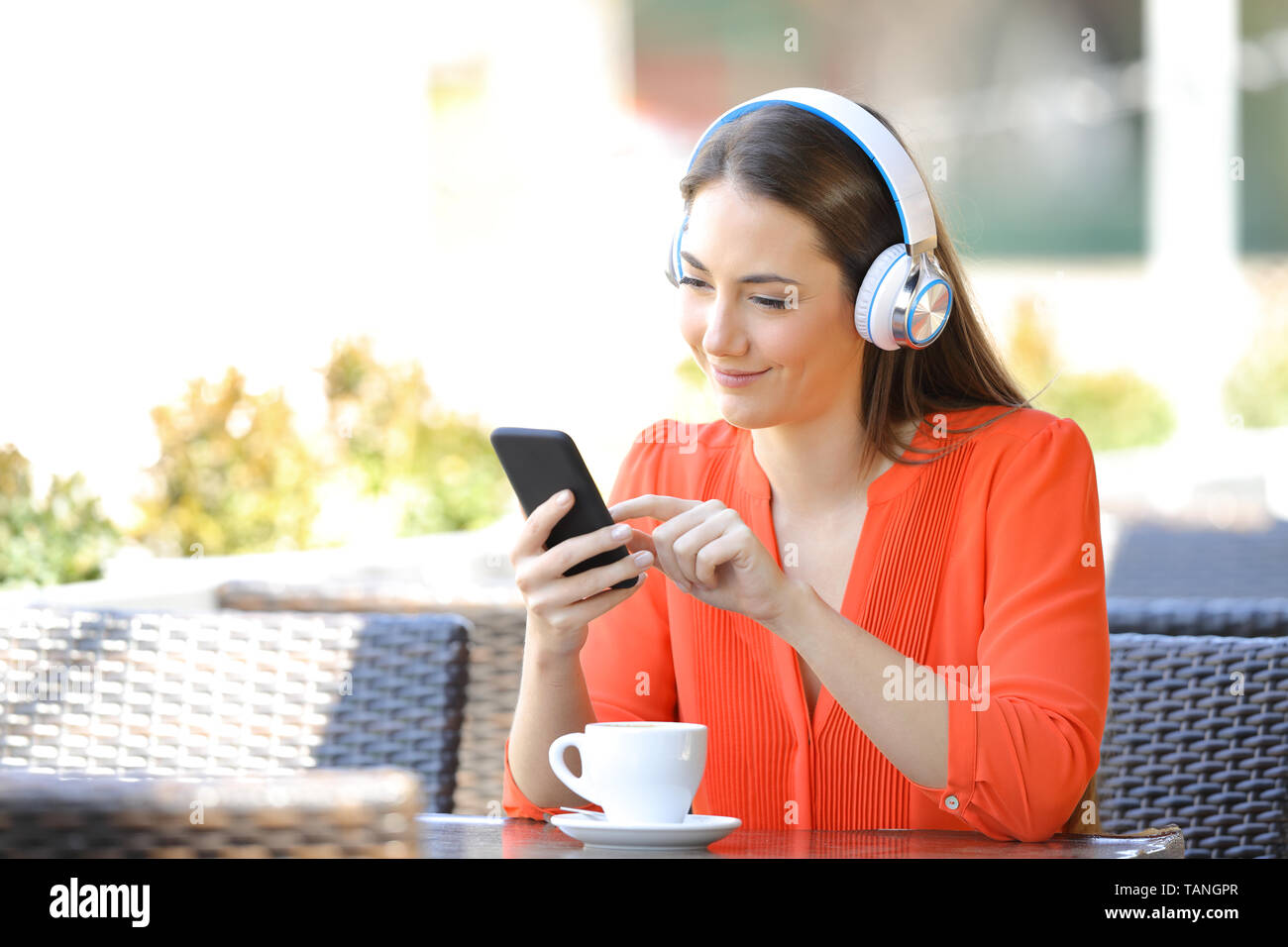 Mujer relajada usando audífonos utilizando un teléfono inteligente para  escuchar música en una tienda de café Fotografía de stock - Alamy