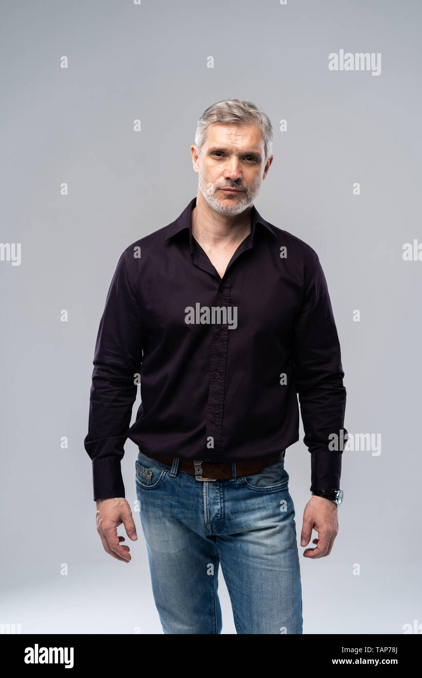Alegre hombre de mediana edad con fondo blanco, vaqueros y camisa negra,  mid shot Fotografía de stock - Alamy
