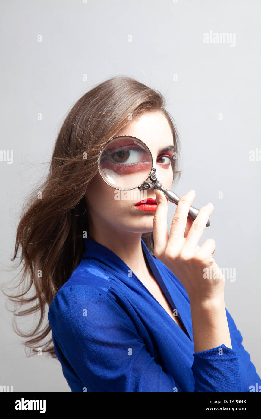 Mujer en azul con lupa sobre Ojo Foto de stock