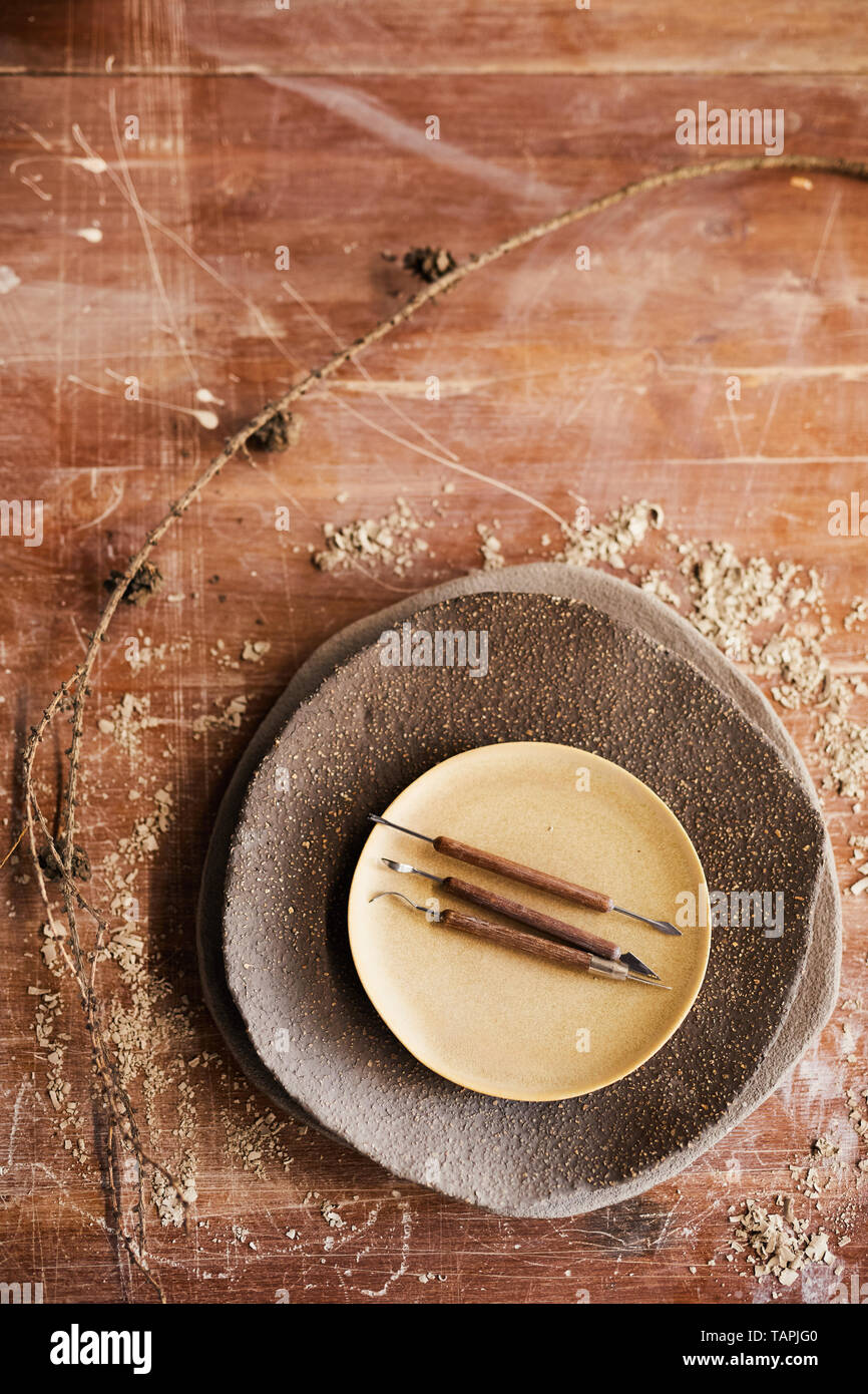 Un alto ángulo de visualización de escalpelos y cuchillas en el apilamiento de placas de cerámica en el cuadro rayado con aserrín Foto de stock
