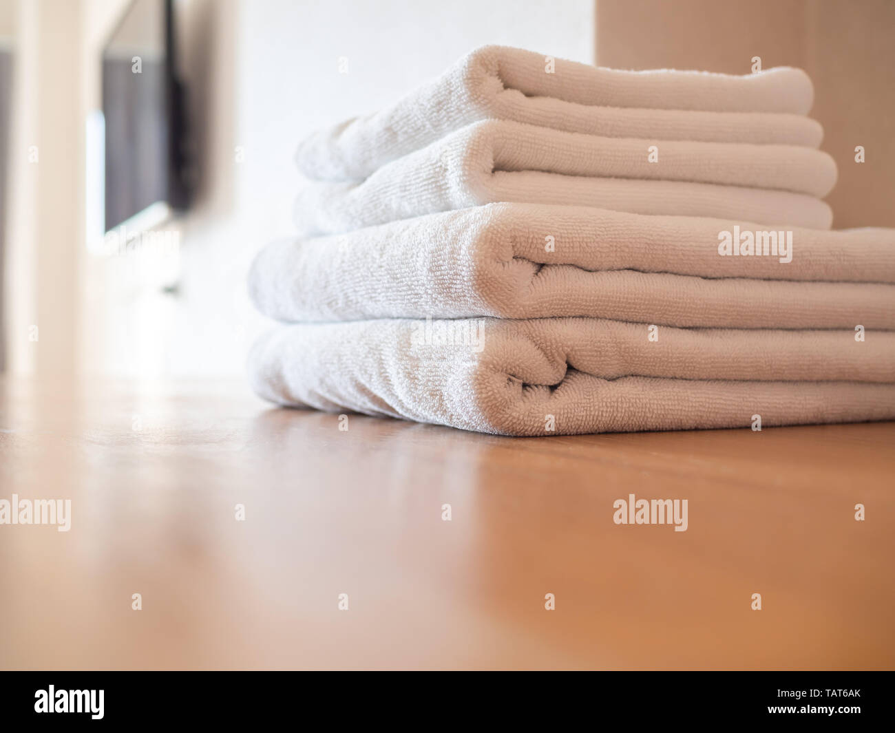 Toallas limpias blanco sobre superficie de madera y la pared blanca de  fondo en hotel Fotografía de stock - Alamy