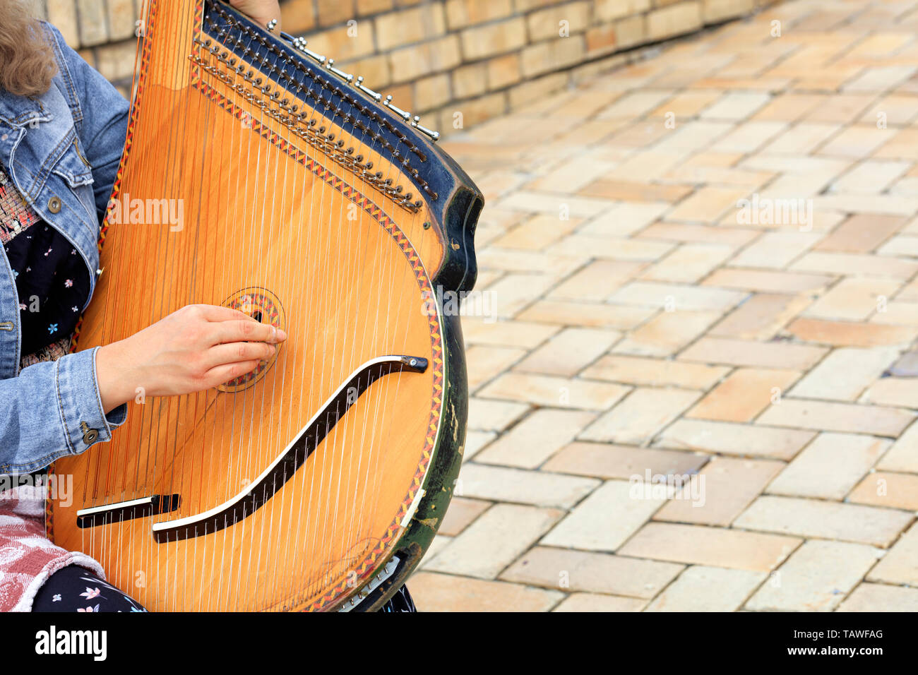 El músico toca el antiguo instrumento musical étnico ucranio bandura ( Pandora) con el telón de fondo de la antigua carretera de adoquines  Fotografía de stock - Alamy