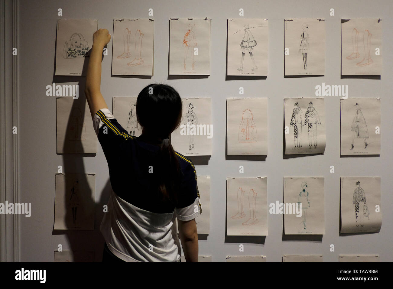 Mujer joven colgando sketch dibujos por SHIATZY CHEN casa de moda que crea "neo-chino chic" subrayó que la artesanía tradicional chino y la fusión de Oriente y Occidente, Taipei, Taiwán. Foto de stock
