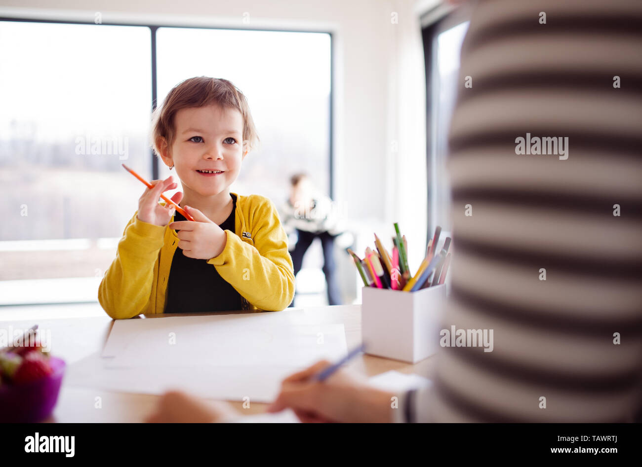 Una pequeña niña madre irreconocible con dibujo en una cocina. Foto de stock