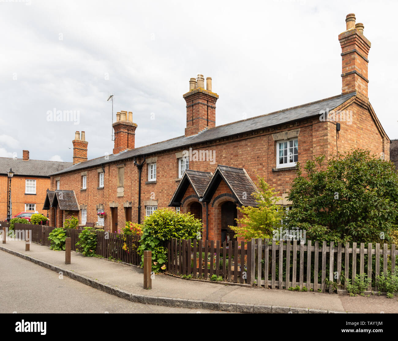 Una fila de seis casas de campo construidas en ladrillo, catalogadas como grado II, en la plaza, Dunchurch, cerca de Rugby, Warwickshire, Reino Unido. Foto de stock
