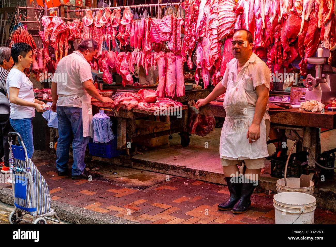 La gente local comprando carne a los carniceros Shop en el mercado alimentario Bowrington Road, Hong Kong, China Foto de stock