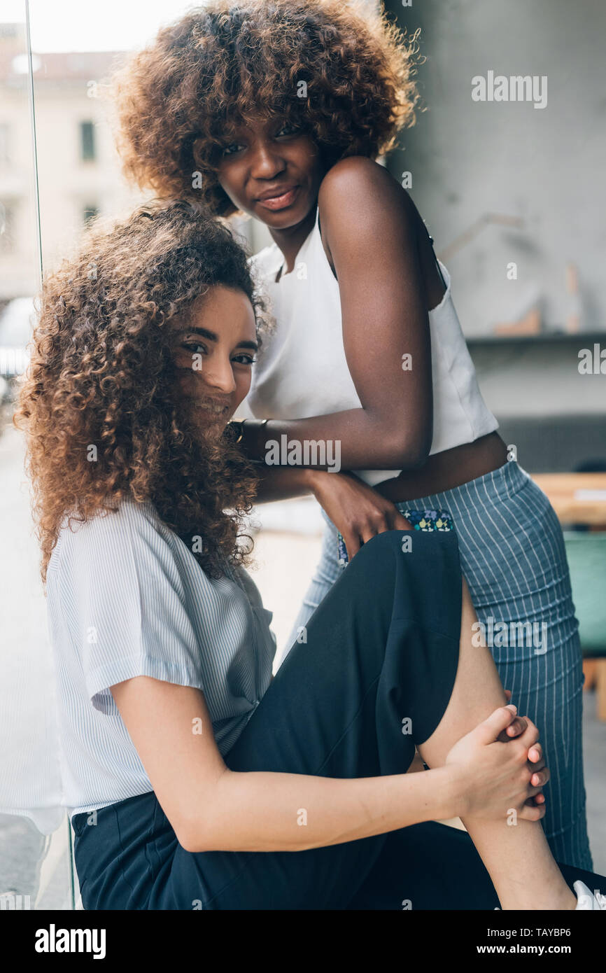 Dos jóvenes multirracial y rizado mujer posando juntos y mirando la cámara-, la nueva generación de jóvenes, la felicidad Foto de stock